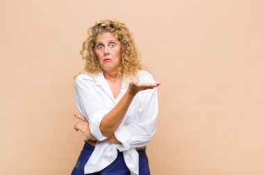 Orta yaşlı bir kadın kafası karışık ve bilgisiz, şüpheli bir açıklama ya da düşünceyi merak ediyor.