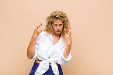 Orta yaşlı bir kadın endişeyle dua ediyor ve endişeli bir bakışla iyi şanslar diliyor.