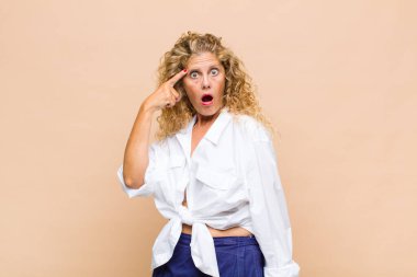 Orta yaşlı kadın şaşırmış, ağzı açık, şok olmuş, yeni bir düşünce, fikir ya da konsept keşfediyor.