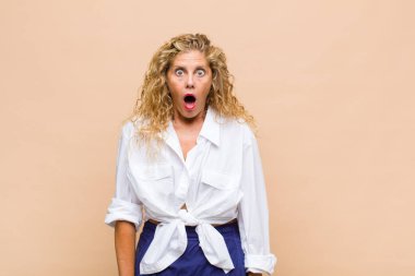 Orta yaşlı kadın korkmuş ve şok olmuş hissediyor, ağzı açık şaşkınlık içinde.