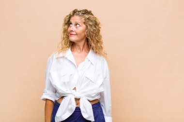 Orta yaşlı kadın merak ediyor, mutlu düşünceler ve fikirler düşünüyor, hayal kuruyor, kenarda yer arıyor.