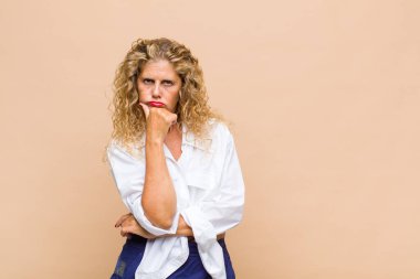 Orta yaşlı kadın ciddi görünüyor, kafası karışık, kararsız ve düşünceli, seçenekler ve seçenekler arasında şüpheci.