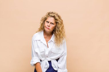 Orta yaşlı bir kadın kafası karışık ve kuşkulu, merak ediyor ya da karar vermeye çalışıyor.