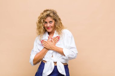 Orta yaşlı bir kadın romantik, mutlu ve aşık, neşeli bir şekilde gülümseyen ve kalbe yakın el ele tutuşan