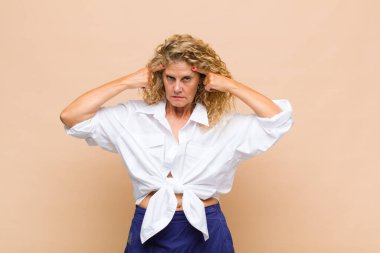 Ciddi ve konsantre görünümlü orta yaşlı bir kadın, beyin fırtınası yapıyor ve zorlu bir sorunu düşünüyor.