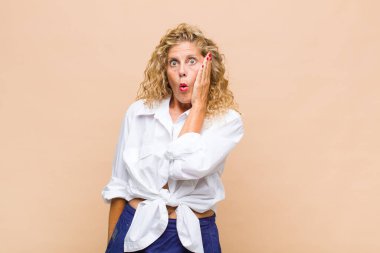 Orta yaşlı bir kadın ağzı açık bir şekilde yüz yüze inanmayarak şok olmuş ve hayrete düşmüş hissediyor.