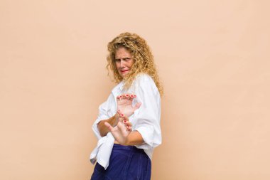 Orta yaşlı bir kadın tiksinmiş ve midesi bulanıyor. İğrenç, kokuşmuş ya da kokuşmuş bir şeyden kaçıyor.