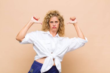 Orta yaşlı bir kadın gururlu, kibirli ve kendinden emin, tatmin olmuş ve başarılı görünüyor, kendini işaret ediyor.