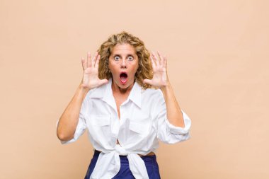 Orta yaşlı bir kadın elleri havada bağırıyor. Öfkeli, sinirli, stresli ve üzgün.