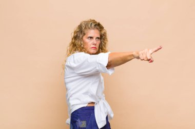 Orta yaşlı bir kadın şaşkın ve şaşırmış hissediyor. Şaşırmış ve ağzı açık bir şekilde hayranlıkla yukarı bakıyor.