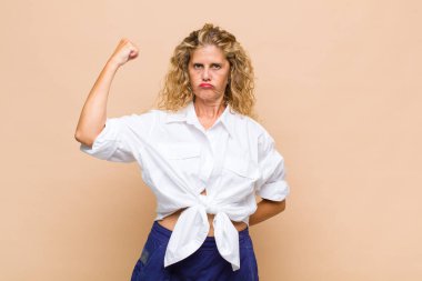 Orta yaşlı kadın ciddi, güçlü ve isyankar hissediyor, yumruğunu kaldırıyor, protesto ediyor ya da devrim için savaşıyor.