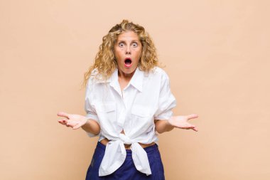 Orta yaşlı bir kadın son derece şok olmuş, şaşırmış, endişeli ve paniklemiş, stresli ve dehşete kapılmış bir şekilde bakıyor.