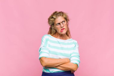 Orta yaşlı bir kadın şüpheye düşüyor ya da düşünüyor, dudağını ısırıyor ve kendini güvensiz ve gergin hissediyor, kenarda yer arıyor.