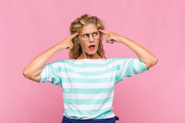 Orta yaşlı bir kadın kafası karışık ya da şüpheci, bir fikre odaklanmış, çok düşünüyor, kenarda boşluklar arıyor.