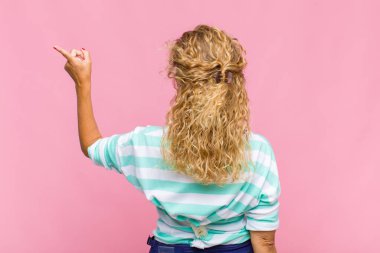 Orta yaşlı kadın dikey görünüm ve kopyalama alanı üzerinde duran ve nesneyi işaret eden