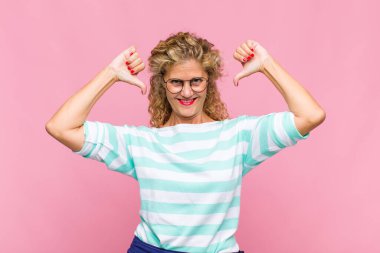 Orta yaşlı bir kadın üzgün, hayal kırıklığına uğramış ya da kızgın görünüyor. Anlaşmazlıkta baş parmağını gösteriyor. Hayal kırıklığına uğramış hissediyor.