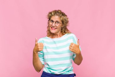 Orta yaşlı bir kadın neşeyle gülümsüyor ve mutlu görünüyor, kaygısız ve pozitif hissediyor.