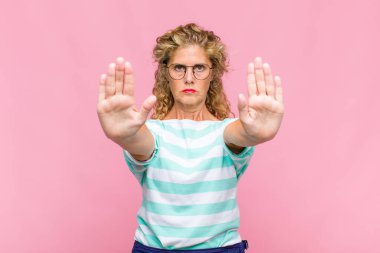 Orta yaşlı kadın ciddi görünüyor, mutsuz, kızgın ve hoşnutsuz giriş yasaklandı ya da her iki avuçta da dur diyor.