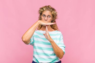 Orta yaşlı bir kadın ciddi, sert, kızgın ve canı sıkkın görünüyor.