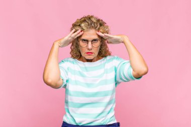 Orta yaşlı bir kadın konsantre olmuş, düşünceli ve ilham verici, beyin fırtınası yapıyor ve hayal kuruyor.