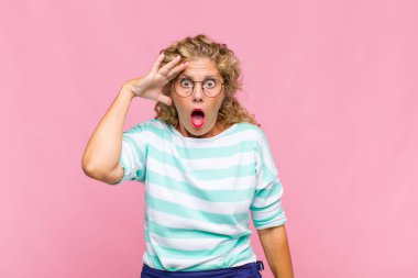 Orta yaşlı kadın mutlu, şaşkın ve şaşırmış görünüyor, gülümsüyor ve inanılmaz ve inanılmaz iyi haberleri fark ediyor.