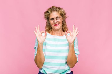 Orta yaşlı bir kadın konsantre olmuş ve meditasyon yapıyor. Tatmin olmuş ve rahatlamış hissediyor. Düşünüyor ya da bir seçim yapıyor.