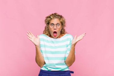 Orta yaşlı bir kadın mutlu, heyecanlı, şaşırmış ya da şaşırmış hissediyor, gülümsüyor ve hayret verici bir şeye şaşırıyor.