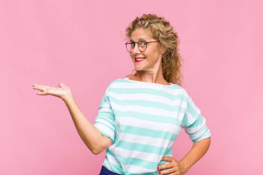 Orta yaşlı kadın gülümsüyor, kendinden emin, başarılı ve mutlu hissediyor, fotokopi alanında fikir veya konsept gösteriyor.