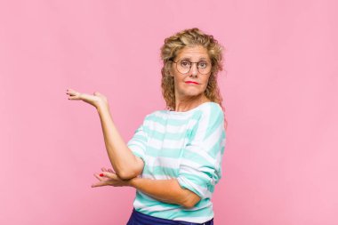 Orta yaşlı kadın gururla ve kendinden emin bir şekilde gülümsüyor, mutlu ve tatmin olmuş hissediyor ve fotokopi alanında bir konsept gösteriyor.