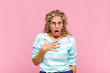 Orta yaşlı kadın şaşkın, şaşkın ve şaşırmış hissediyor, elleri göğsünde ve ağzı açık, kim olduğunu söylüyor, ben mi??