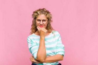 Orta yaşlı kadın gülümsüyor, hayattan zevk alıyor, mutlu, arkadaş canlısı, tatmin olmuş ve tasasız.