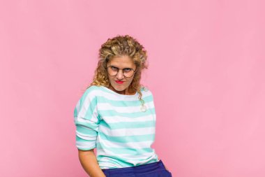 Orta yaşlı bir kadın gururlu, kendinden emin, havalı, küstah ve küstah görünüyor, gülümsüyor, başarılı hissediyor.