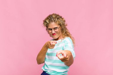 Orta yaşlı bir kadın kendini mutlu, havalı, tatmin olmuş, rahat ve başarılı hissediyor, kameraya bakıyor, seni seçiyor.