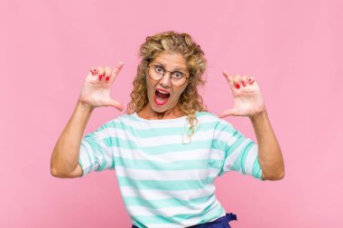 Orta yaşlı bir kadın iki eliyle kendi gülüşünü çiziyor, olumlu ve mutlu görünüyor, sağIık kavramı