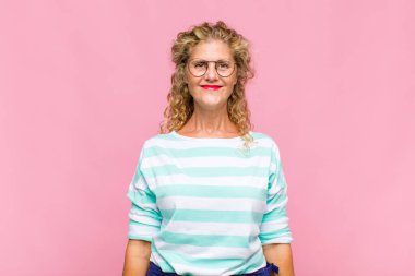 Orta yaşlı kadın pozitif ve kendinden emin gülümsüyor. Tatmin olmuş, arkadaş canlısı ve mutlu görünüyor.