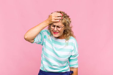 Orta yaşlı bir kadın gülüyor ve alnına şaplak atıyor. Unuttum ya da aptalca bir hataydı. 