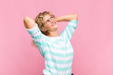 Orta yaşlı kadın gülümsüyor ve rahatlıyor, tatmin oluyor ve kaygısız, neşeli ve rahatlatıcı.