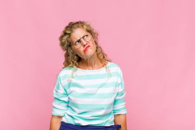 Orta yaşlı kadın şaşkın ve şaşkın görünüyor, merak ediyor veya bir sorunu çözmeye çalışıyor veya düşünüyor.