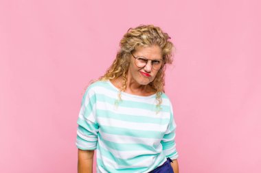 Orta yaşlı bir kadın mutlu ve arkadaş canlısı görünüyor, gülümsüyor ve sana olumlu bir tavırla göz kırpıyor.