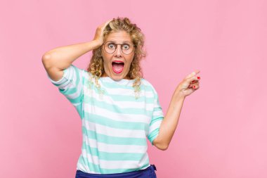 Orta yaşlı bir kadın gülüyor, mutlu, pozitif ve şaşırmış görünüyor, yanal fotokopi alanını işaret eden harika bir fikrin farkına varıyor.