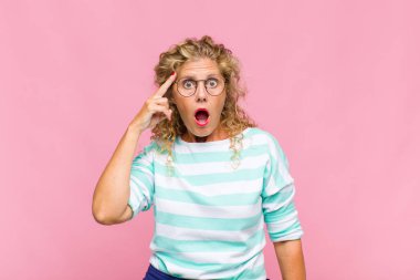 Orta yaşlı kadın şaşırmış, ağzı açık, şok olmuş, yeni bir düşünce, fikir ya da konsept keşfediyor.