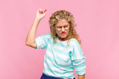 Orta yaşlı bir kadın kızgın agresif bir ifadeyle kameraya bakıyor. Öfkeli, deli bir patron gibi görünüyor.