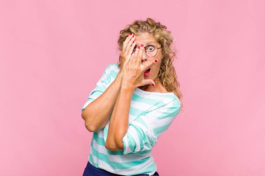 Orta yaşlı bir kadın korkmuş ya da utanmış hisseder. Gözleri yarı kapalı, yarı çıplak bir şekilde dikizler ya da gözetler.