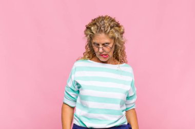 Orta yaşlı kadın şaşkın ve şaşkın görünüyor. Sinirli bir hareketle dudağını ısırıyor. Sorunun cevabını bilmiyor.