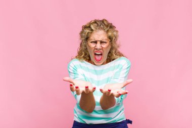 Orta yaşlı kadın umutsuz ve sinirli görünüyor, stresli, mutsuz ve sinirli, bağırıyor ve çığlık atıyor.