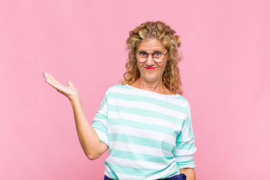 Orta yaşlı bir kadın mutlu, şaşırmış ve neşeli, pozitif bir tavırla gülümsüyor, bir çözüm ya da fikir buluyor.