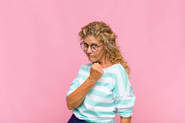 Orta yaşlı bir kadın mutlu, pozitif ve başarılı hissediyor, bir meydan okumayla karşılaştığında motive oluyor veya iyi sonuçları kutluyor.