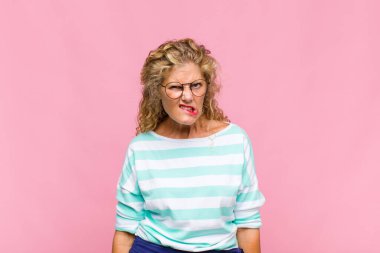 Orta yaşlı bir kadın kafası karışık ve kuşkulu, merak ediyor ya da karar vermeye çalışıyor.