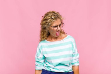 Orta yaşlı bir kadın tiksinmiş ve rahatsız olmuş hissediyor. Dilini dışarı çıkarıyor. İğrenç ve iğrenç bir şeyden hoşlanmıyor.