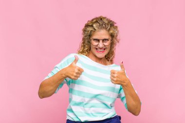 Orta yaşlı kadın mutlu, pozitif, kendine güvenen ve başarılı bir şekilde gülümsüyor.